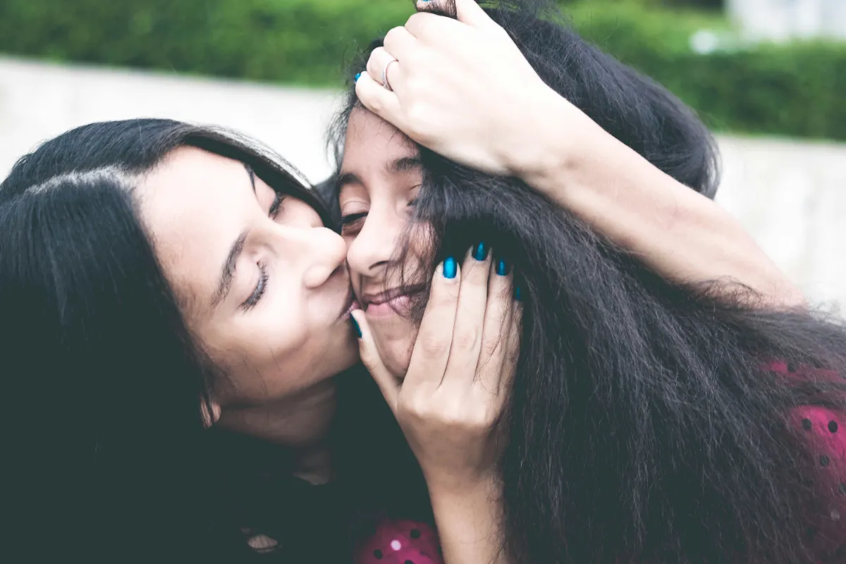 A mother giving her teenage daughter an affectionate kiss on the cheek